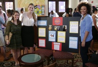 Students stand in front of a presentation on poster board
